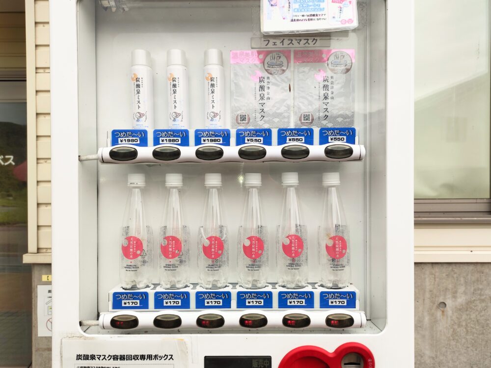 株式会社ハーベスの工場前にある「奥会津金山 天然炭酸の水」が販売されている自動販売機の画像