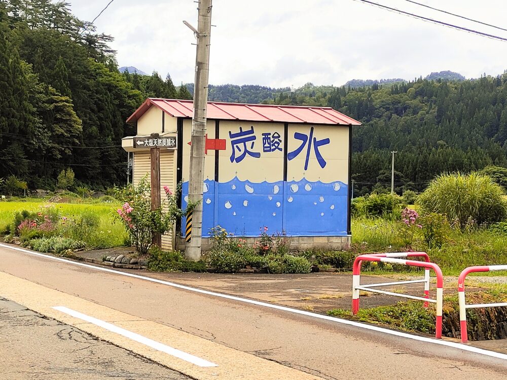 「炭酸水」と文字が書かれた赤いトタン屋根の小屋の画像