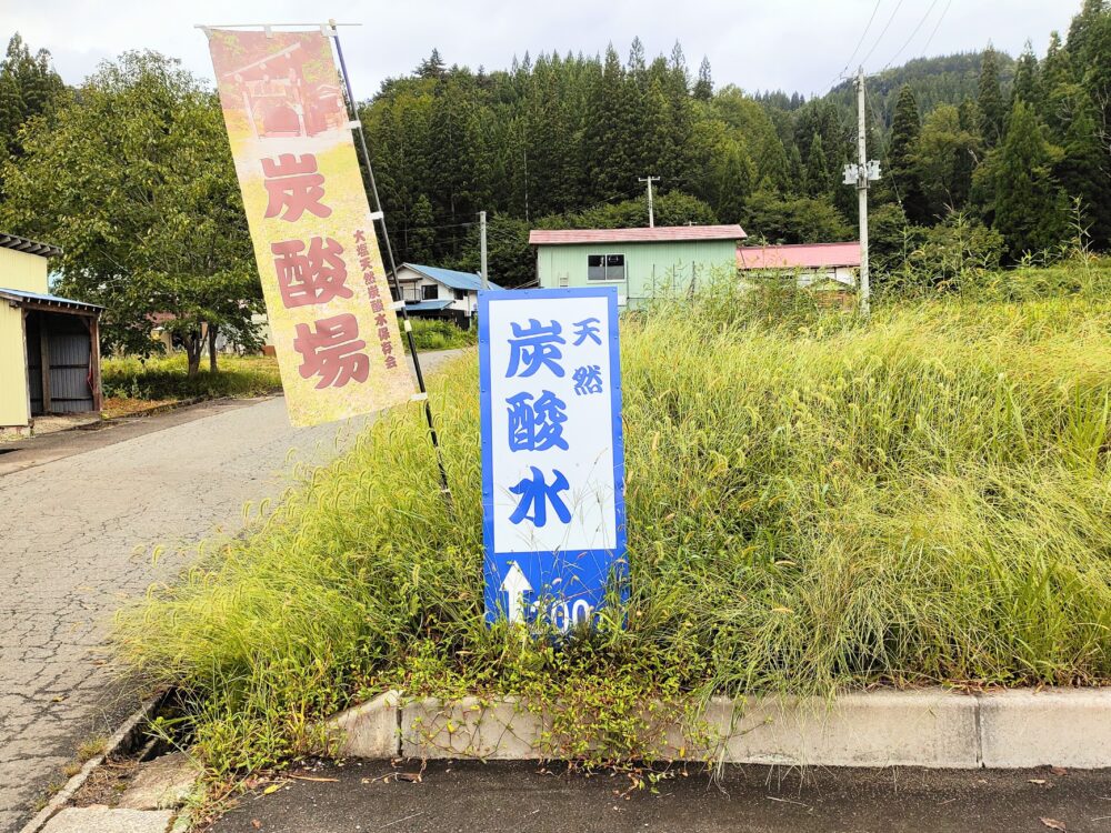 駐車場内にある「天然炭酸水」と書かれた青い立て看板の画像