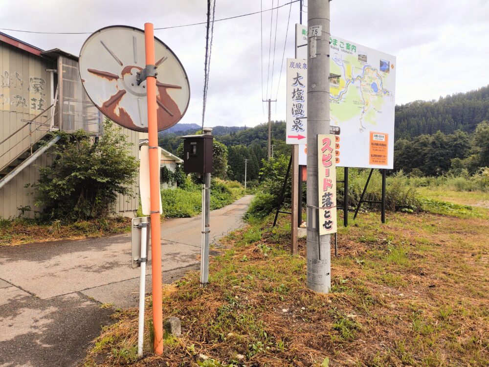 看板の裏にある大塩温泉につながる舗装された小さな道の画像