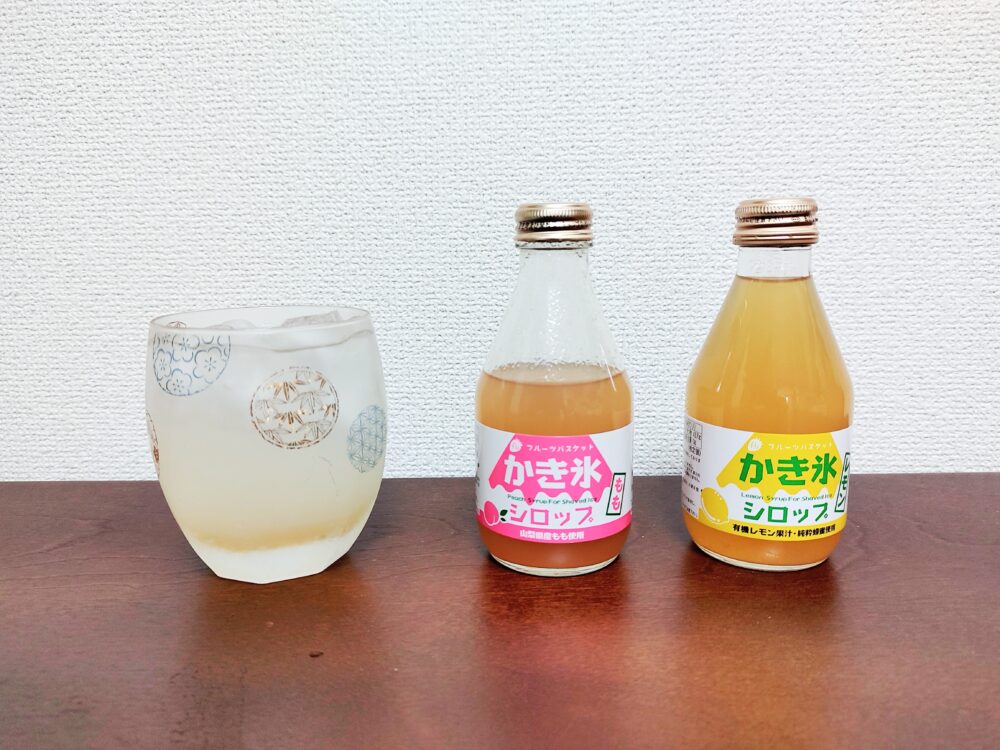 もも味とレモン味のかき氷シロップと、それらで作った炭酸ドリンクを注いだ底の丸いロックグラスを並べた画像