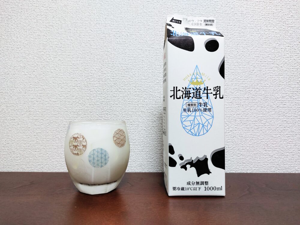 牛乳の紙パックと、それで作った炭酸ドリンクを注いだ底の丸いロックグラスを並べた画像